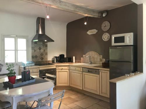 a kitchen with a white table and a refrigerator at Mas Boudeissoun - Cœur de cerise - Baignade à 600 m in Mormoiron