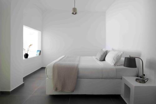 a white bedroom with a white bed and a table at Marizan Caves & Villas in Oia