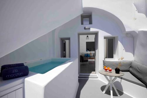 a white bathroom with a plunge pool and a table at Marizan Caves & Villas in Oia