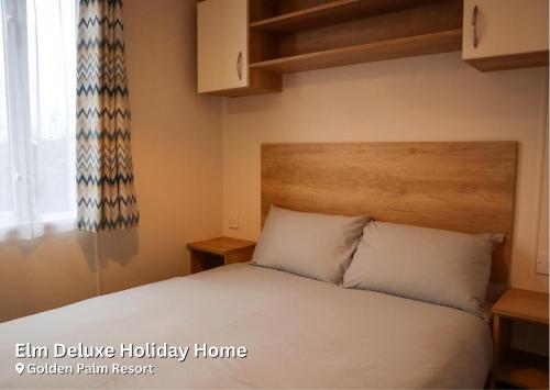 1 dormitorio con 1 cama con cabecero de madera en Elm Deluxe Holiday Home, en Chapel St. Leonards
