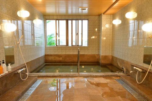 a large bathroom with a shower and a pool of water at Rakuchin in Naha