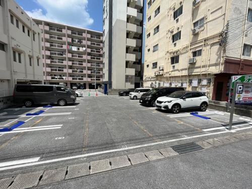 a parking lot with parked cars in a city at Rakuchin in Naha