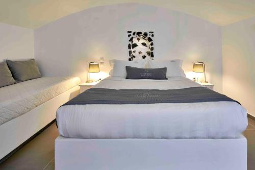 a bedroom with a large white bed and two lamps at Marizan Caves & Villas in Oia