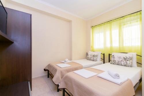 two beds in a small room with a tv at Evdokia's Apartments and Rooms in Neos Marmaras