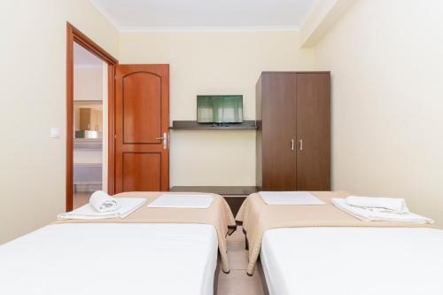 a room with two beds and a cabinet at Evdokia's Apartments and Rooms in Neos Marmaras