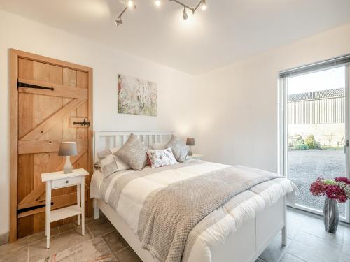 a white bedroom with a bed and a window at Pightle Cottage in Poringland