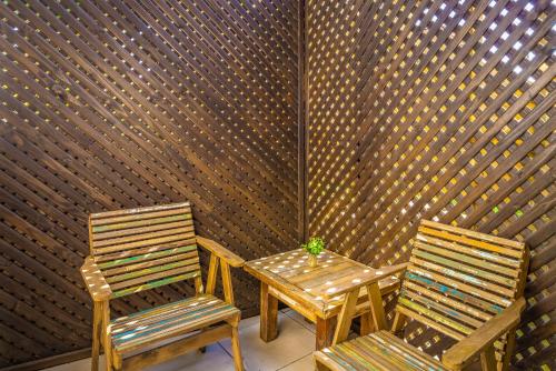 two chairs and a table in front of a wall at Pousada Flor de Lotus in Praia do Rosa