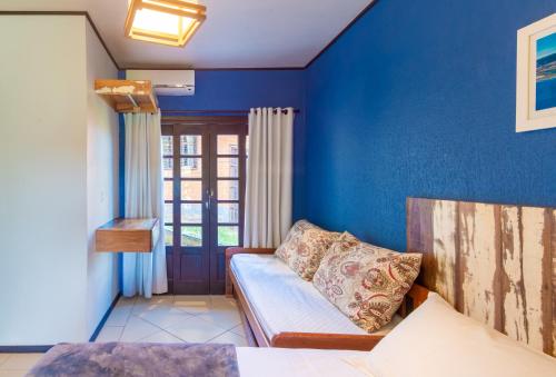 a blue room with a bed and a couch at Pousada Flor de Lotus in Praia do Rosa