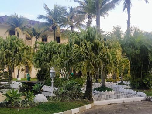 un patio con palmeras y un edificio en Seu lar na praia das Toninhas em Ubatuba, en Ubatuba