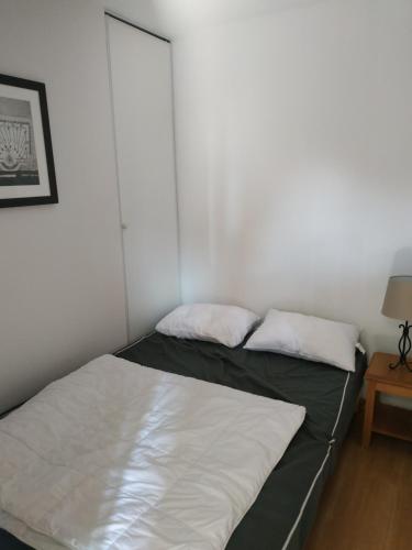 Ce lit se trouve dans un dortoir doté d'un mur blanc. dans l'établissement L'APPARTEMENT DU BONHEUR, à Super-Besse