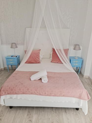 a bedroom with a bed with pink sheets and two blue tables at Casa da Alagoinha in Vila Nova de Milfontes
