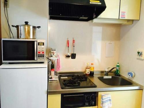a small kitchen with a microwave and a sink at 桜の宿28 square meter king size bed with sofa bed, garden room102 in Tokyo