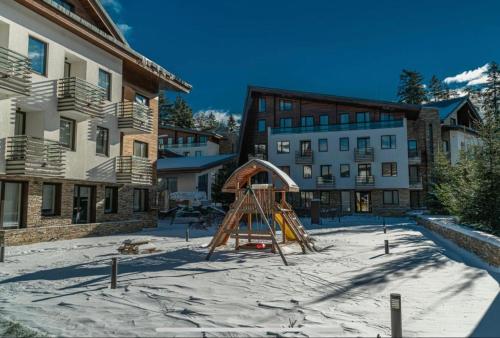 a playground in the snow in front of a building at Lodge Euphoria Apartment in Borovets
