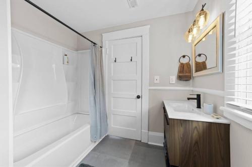 a white bathroom with a sink and a tub at Beautiful Historical home in Fisher Park! 4BR 3BA in Greensboro