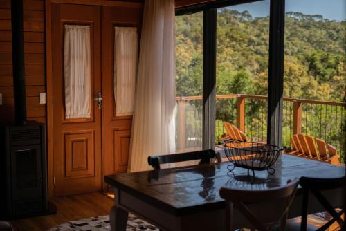 a living room with a table and a large window at Cabanas Urubici in Urubici