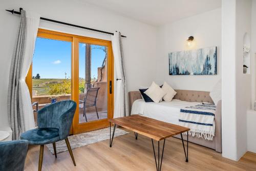 a bedroom with a bed and a table and a window at Sirena Vineyard Resort in Paso Robles