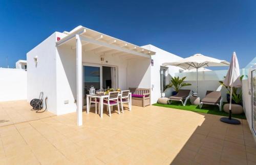 a patio with a table and chairs and an umbrella at The Little White House, Suite Flower Beach 9 in Playa Honda