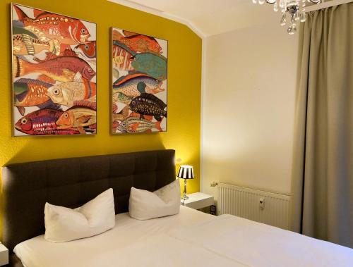 オストゼーバート・ディアーハーゲンにあるOstsee Ferienappartements Dierhagen-Strand klein & feinのベッドルーム1室(壁に絵画3点が飾られたベッド1台付)