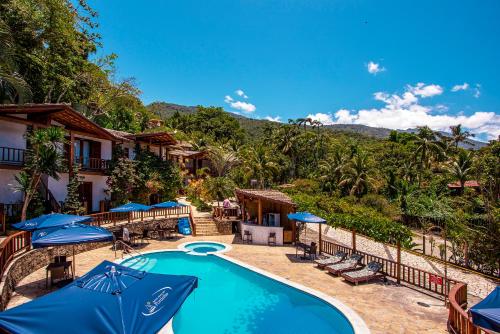 a resort with a swimming pool with blue umbrellas at Hotel Praia do Portinho in Ilhabela