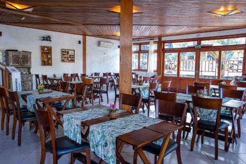 a dining room with tables and chairs and windows at Hotel Praia do Portinho in Ilhabela