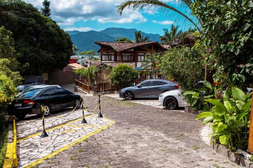 two cars parked in front of a house at Hotel Praia do Portinho in Ilhabela
