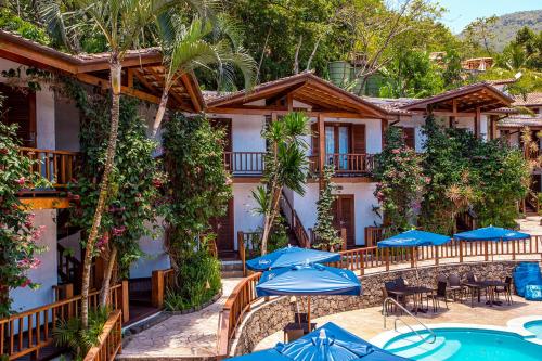 a hotel with tables and umbrellas in front of it at Hotel Praia do Portinho in Ilhabela