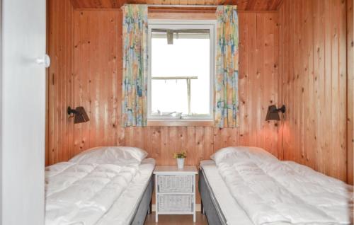 BjerregårdにあるAwesome Home In Hvide Sande With Kitchenのウッドウォールと窓が備わるドミトリールームのベッド2台分です。