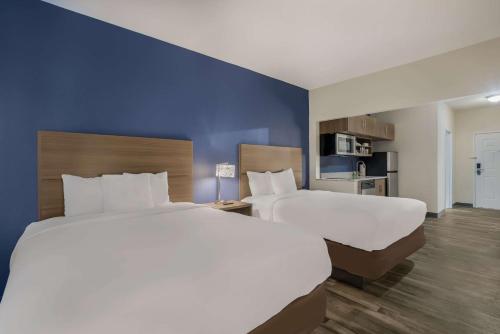 a hotel room with two beds and a blue wall at MainStay Suites Joliet I-80 in Joliet