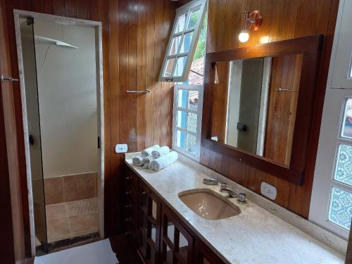 a bathroom with a sink and a mirror and a shower at Pousada Solar Azul in Miguel Pereira