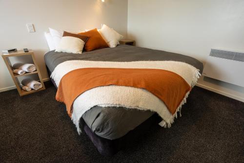 a bedroom with a large bed with an orange blanket at GLENALMOND Country Motels in Harihari