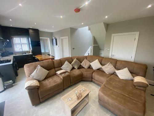 a living room with a brown couch and a table at Country Cottage close to the city. in Newry