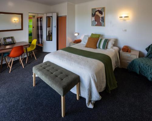 a bedroom with a bed and a desk and a chair at GLENALMOND Country Motels in Harihari