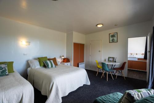 Habitación de hotel con 2 camas, mesa y sillas en GLENALMOND Historic Homestead & Alpine Country Stay en Harihari
