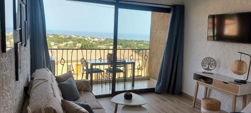 a living room with a couch and a balcony with a table at Casa Mar, studio 4P, vue mer, Sant'Ambroggio, Lumio in Lumio
