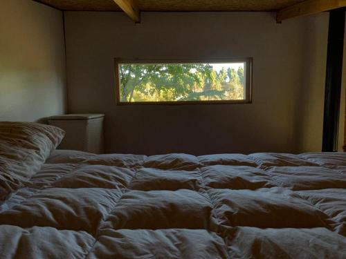 an unmade bed in a room with a window at Tiny House, Cabaña in Coihaique