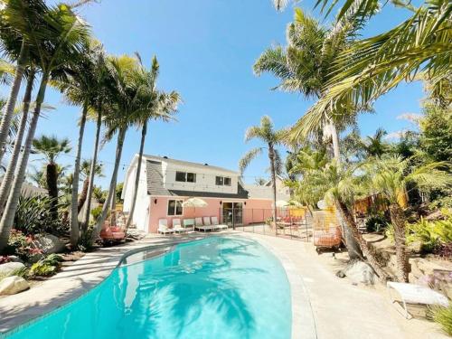 una piscina frente a una casa con palmeras en Pink Paradise Inn - 5 BR Fun Retro Home w/ Pool, en Oceanside
