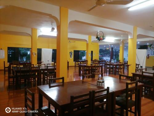 a restaurant with wooden tables and chairs and yellow walls at Hotel Santa María Homun in Homún