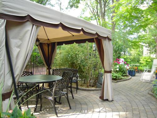a patio with a table and chairs under a tent at L'Arvidienne Couette et Café in Quebec City