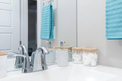 a bathroom counter with a sink with toothbrushes and a mirror at Modern & Stylish 2-Bedroom Unit in Edmonton