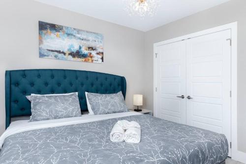 a bedroom with a bed with a blue headboard and two shoes at Modern & Stylish 2-Bedroom Unit in Edmonton