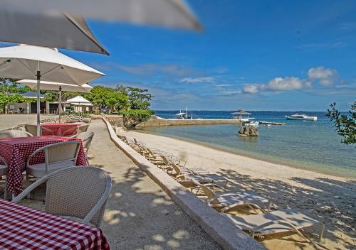 an empty beach with tables and chairs and the ocean at Plantation Bay Resort and Spa in Mactan