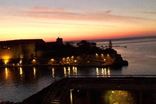 un bateau est amarré dans l'eau au coucher du soleil dans l'établissement Appartement Bouga inville Vue sur mer et château, à Brest
