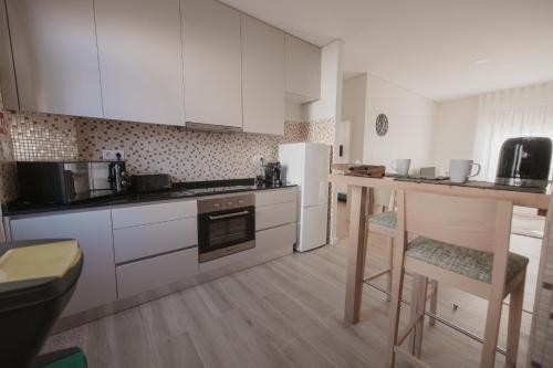 a kitchen with white cabinets and a table and chairs at Albina's Guest House in Leça da Palmeira