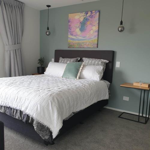a bedroom with a bed with white sheets and pillows at Piwakawaka Suite in Balclutha