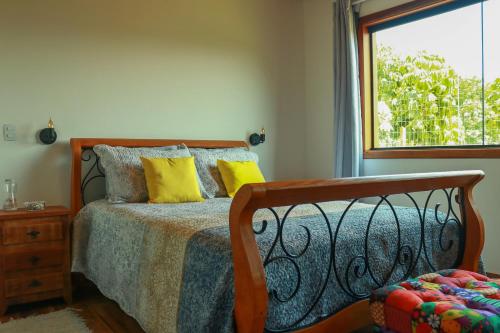 Un dormitorio con una cama con almohadas amarillas y una ventana en Linda vista para as montanhas a 5 min da cidade, en Santo Antônio do Pinhal