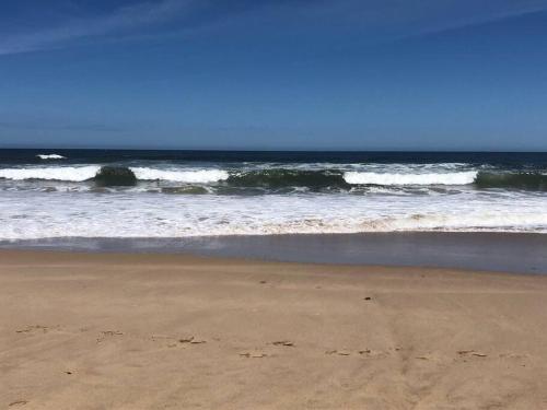 a sandy beach with waves in the ocean at Family Tides - Old Bar Holiday Rentals in Old Bar