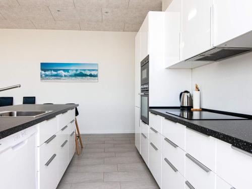 a kitchen with white cabinets and black counter tops at 10 person holiday home in Sjølund-By Traum in Sjølund