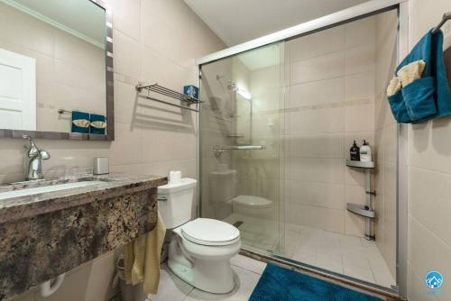 a bathroom with a toilet and a glass shower at Aruba Condo The Pearl - At Eagle Beach - minute walk! in Palm-Eagle Beach
