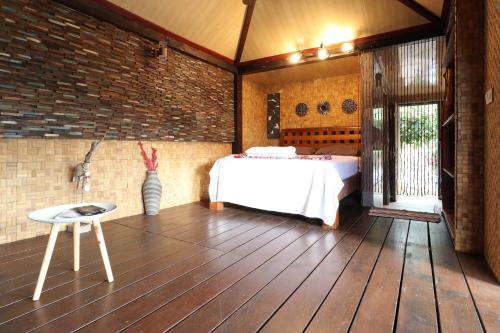 a room with a bed on a wooden floor at KIA ORA LODGE in Afaahiti