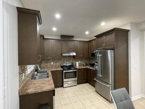 a kitchen with wooden cabinets and stainless steel appliances at Luxury 4-Bedrooms Home… in Brampton